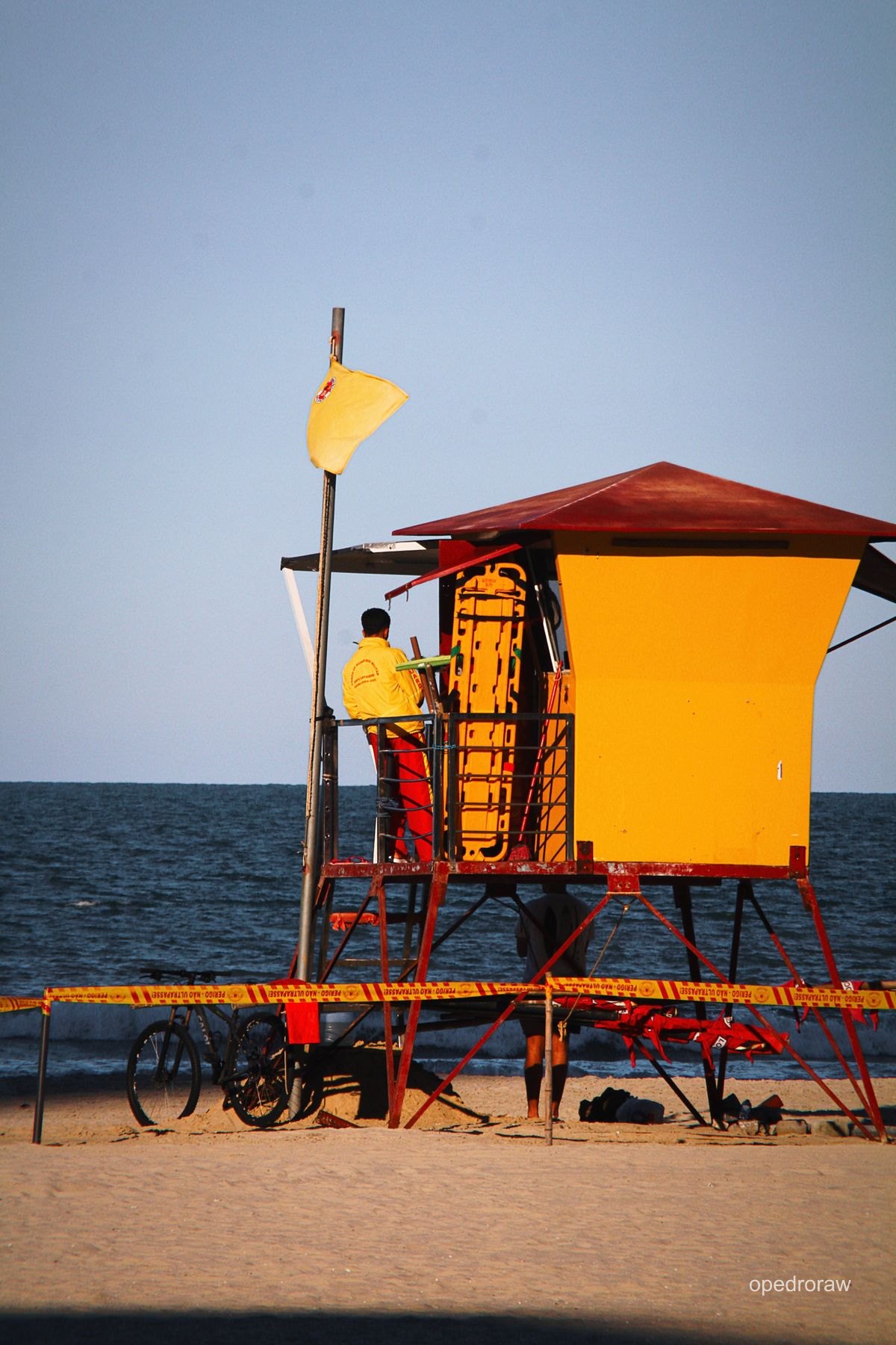 Posto amarelo de salva-vidas com o mar ao fundo
